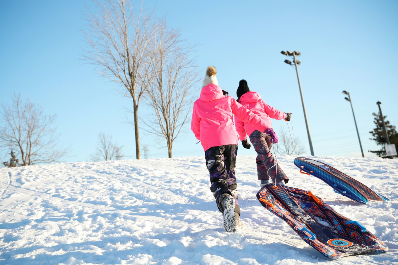 雪の丘をソリを引いて駆け上がる子供たち(冬の活動量)