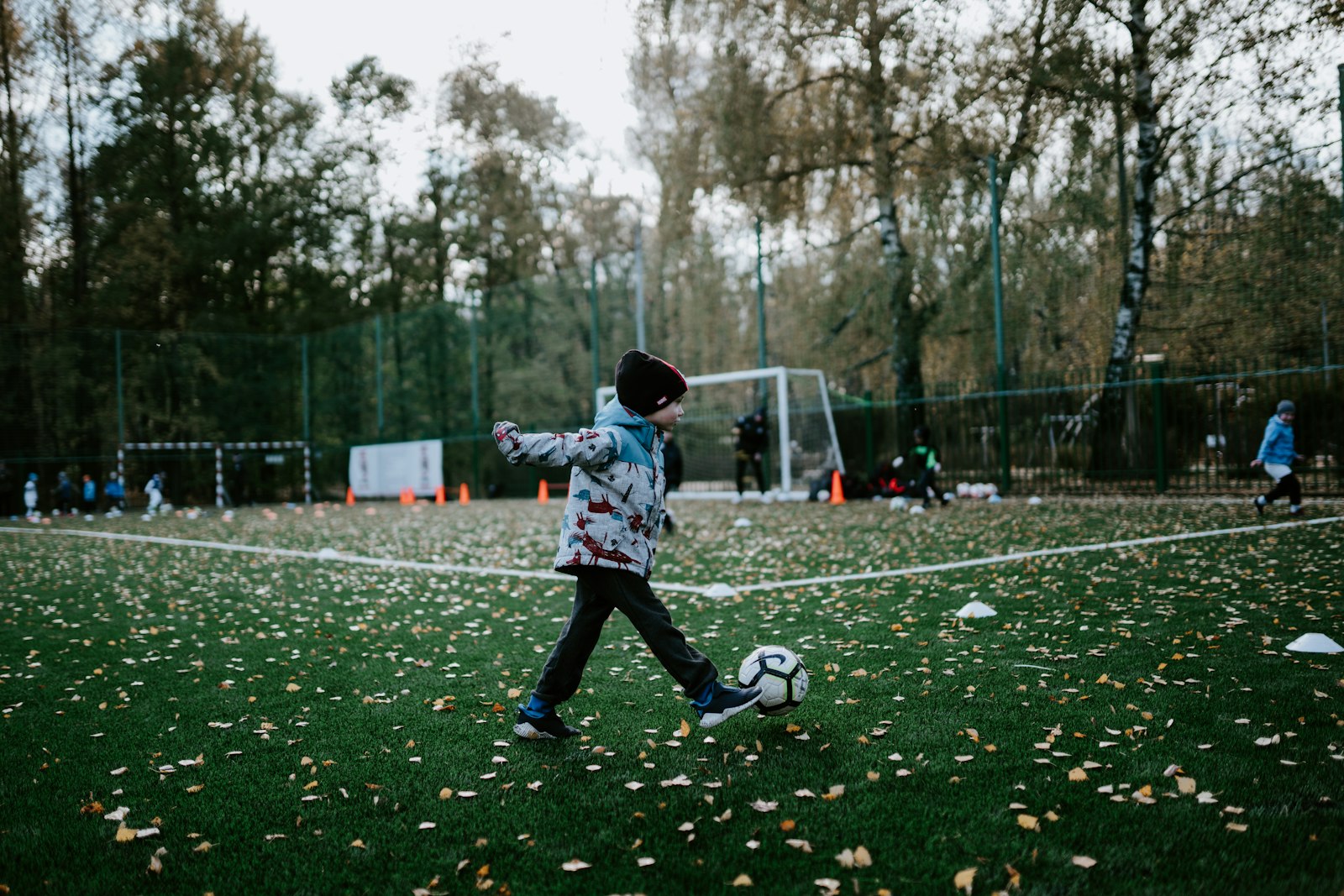 冬の寒いグラウンドでサッカーの練習をする小学生