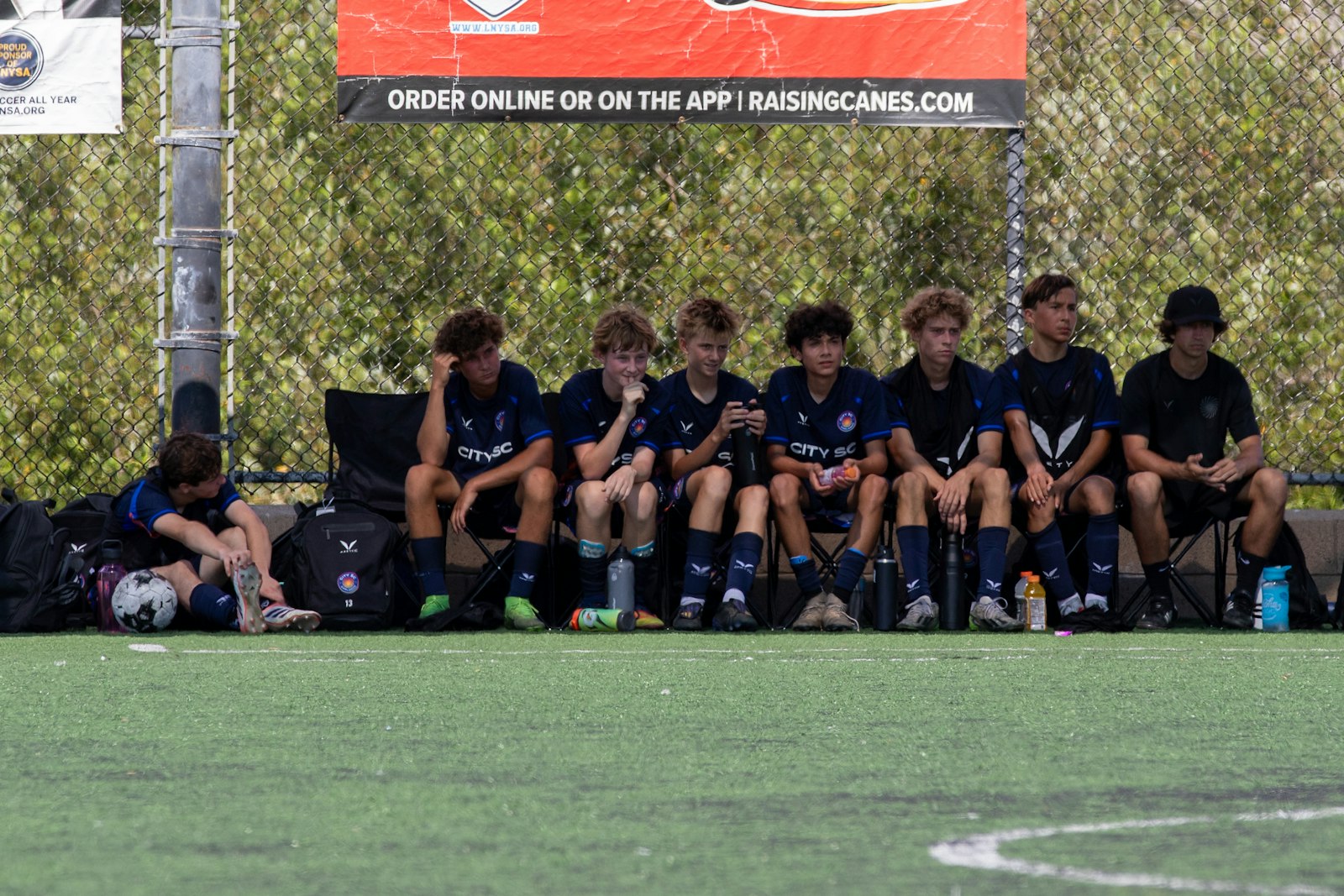 新人戦が終わった後、ベンチに座る少年サッカー選手たち。大会後にやる気が落ちる端境期のイメージ