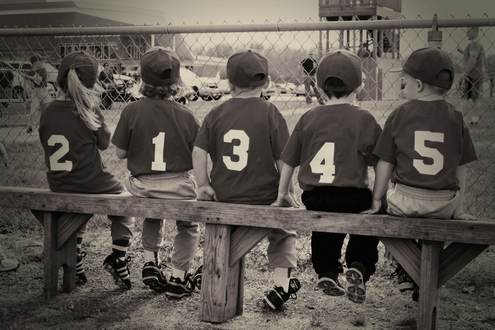ベンチに並んで座る少年野球のユニフォーム姿の子どもたち