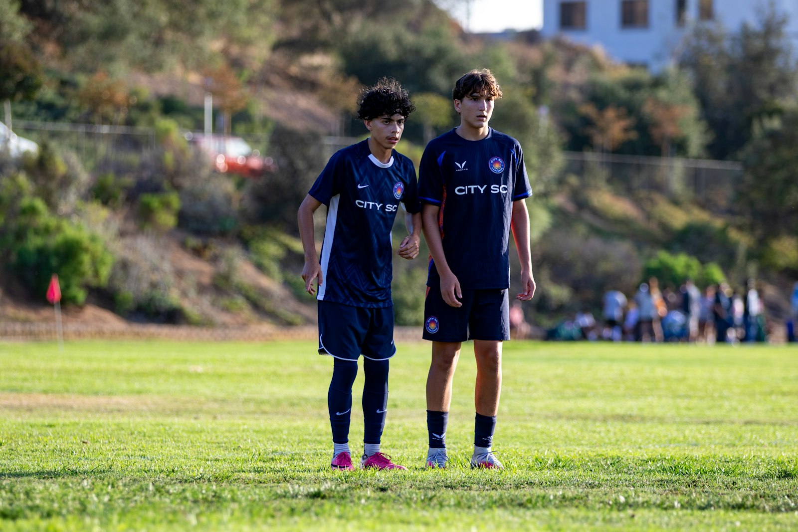 仲の良い友達と並んでグラウンドに立つサッカー少年